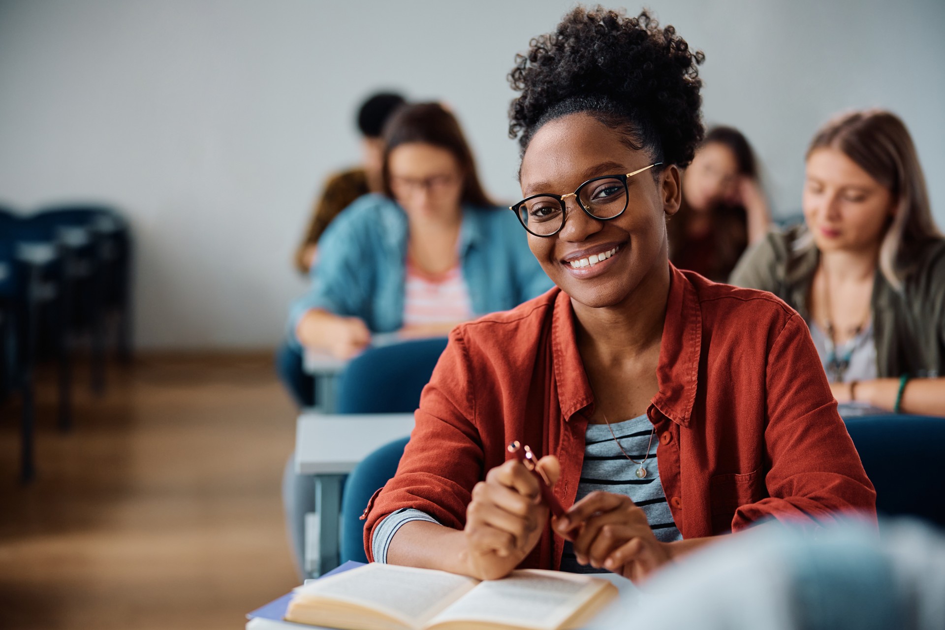 Happy black females student during a class in lecture hall looking at camera.